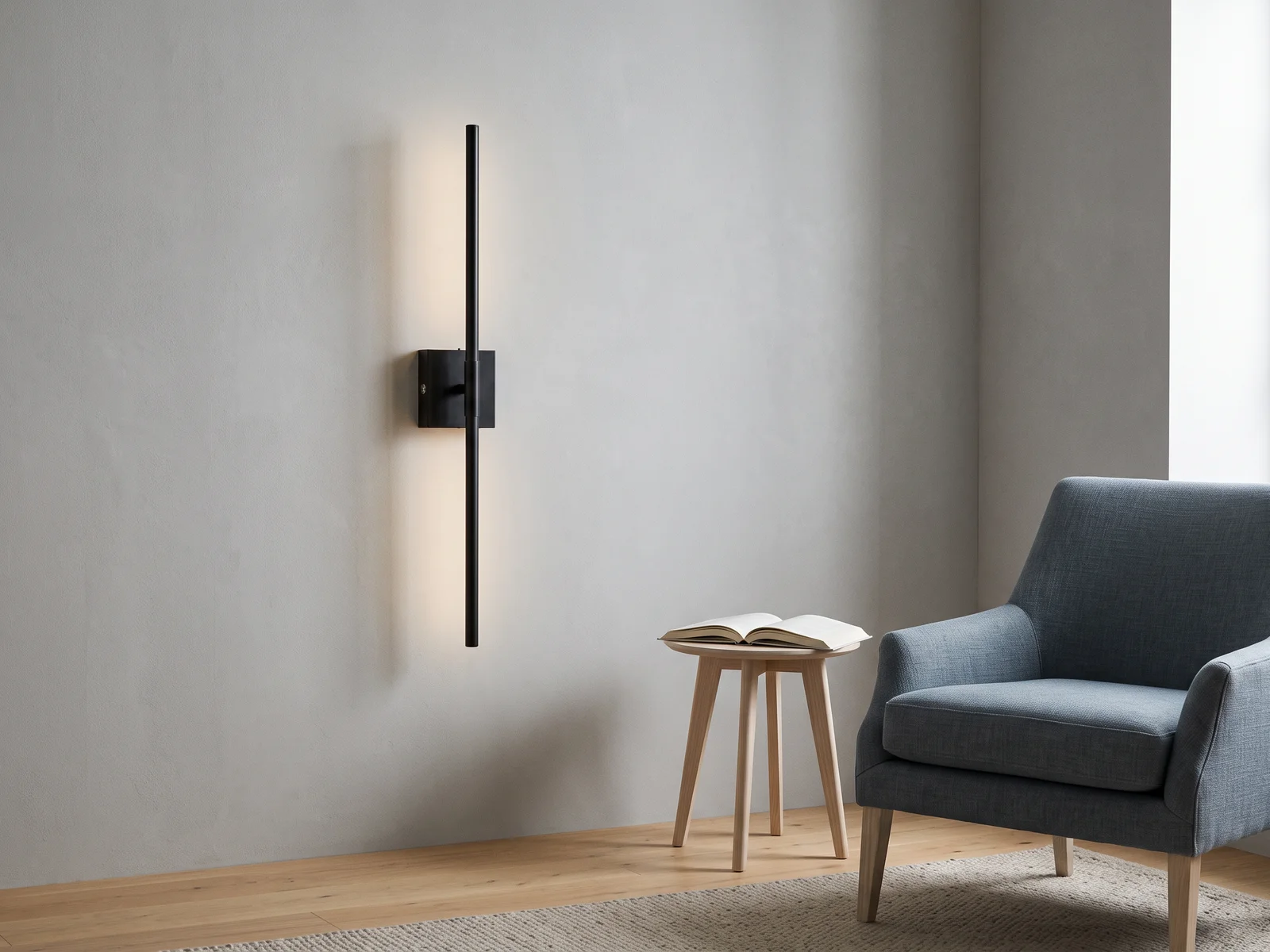 Illustrative black rechargeable wall sconce beside a blue reading chair