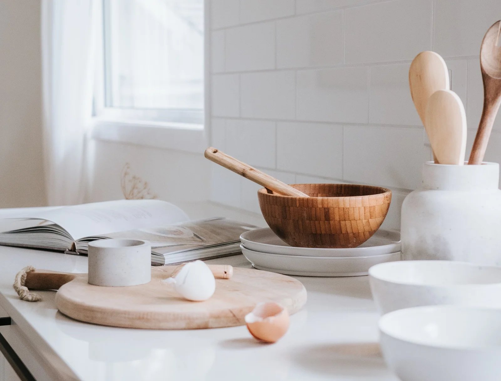 Kitchen counter with wooden utensils, bowls and an open cookbook