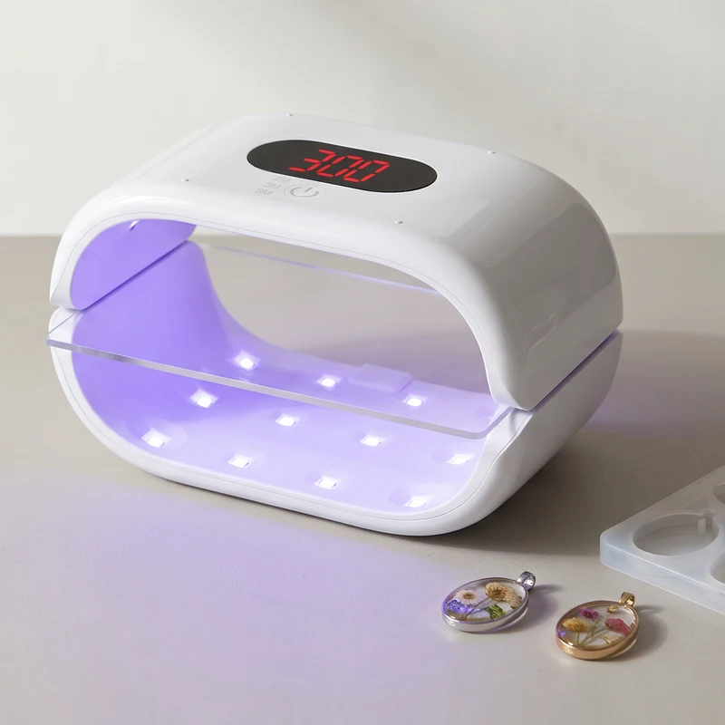 GISTAR white double-sided UV lamp sitting on a workbench beside resin jewelry